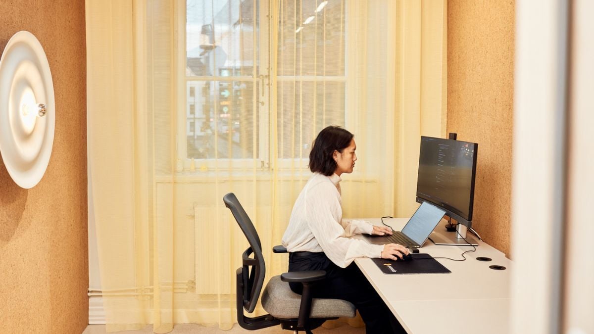 Tjej som sitter och jobbar på sin dator i ett mötesrum